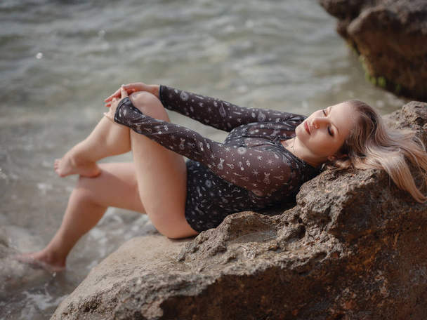 Retrato de atractiva mujer rubia americana con el pelo largo posando en la playa rocosa. Hermoso más tamaño - Foto, Imagen