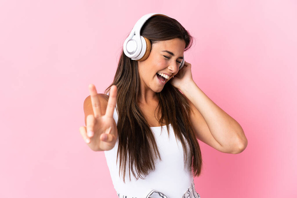 Jovem brasileira isolada no fundo rosa ouvindo música e cantando
 - Foto, Imagem