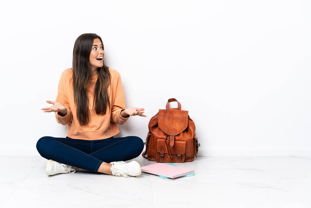 Young student brazilian woman sitting on the floor with surprise facial expression - Photo, Image