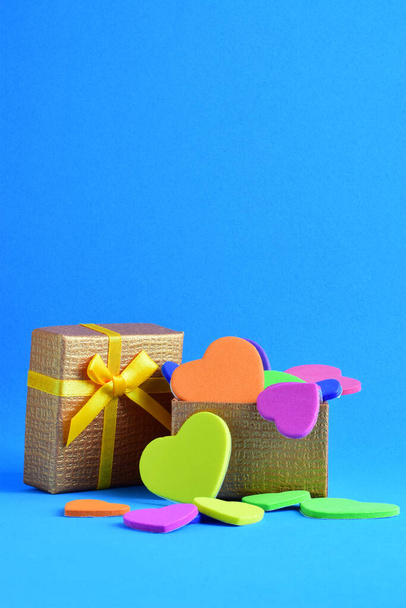 Love, Valentine's Day. Colored hearts inside a gift box and scattered on a blue background. Vertical shot. - Photo, Image