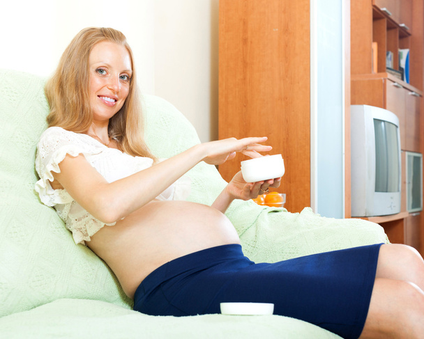 Щаслива вагітна жінка використовує крем
 - Фото, зображення