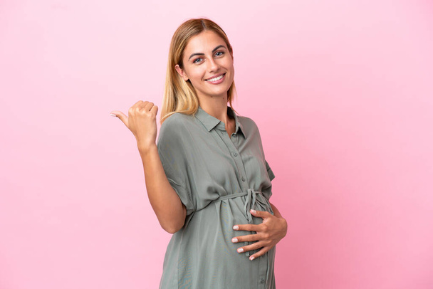 Giovane donna uruguaiana isolata su sfondo blu incinta e con pollice in su - Foto, immagini