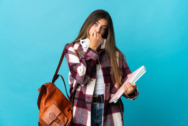 Young student woman isolated on blue background having doubts - Foto, afbeelding