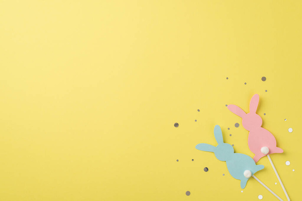 Top view of two rabbits pink and blue one with confetti on the isolated yellow background copyspace - Foto, Imagem