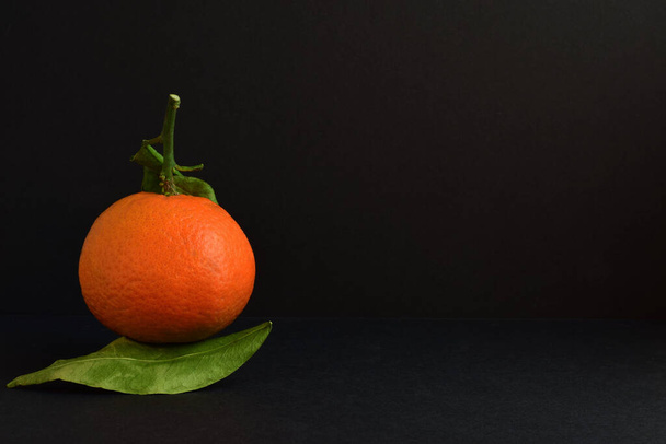 Tangerine με τα φύλλα του, μπροστινή όψη, μαύρο φόντο με χώρο. - Φωτογραφία, εικόνα