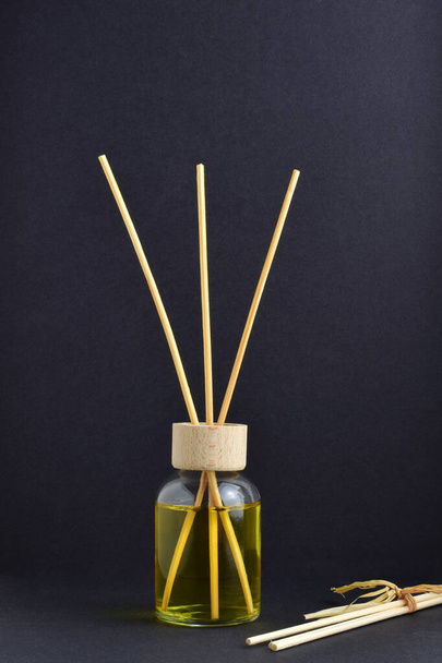 Air freshener with thin wooden sticks on dark background. - Photo, Image