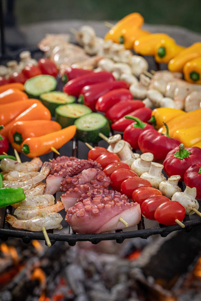 Tasty and healthy grilled shashlik on grill grate with fire. Grilled skewer with vegetables and seafoods. - Fotó, kép