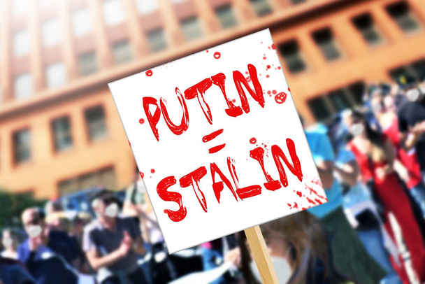  Девушка с политическим плакатом Послание Путина Игалю Сталину на митинге протеста. Репортерское фото войны между Россией и Украиной - Фото, изображение