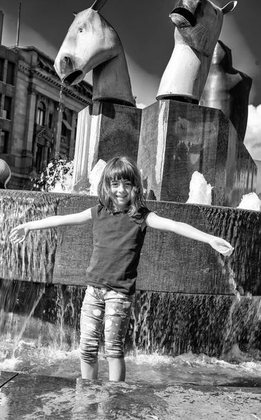 Young girl refreshing in a city fountain protecting from summer heat - Photo, Image