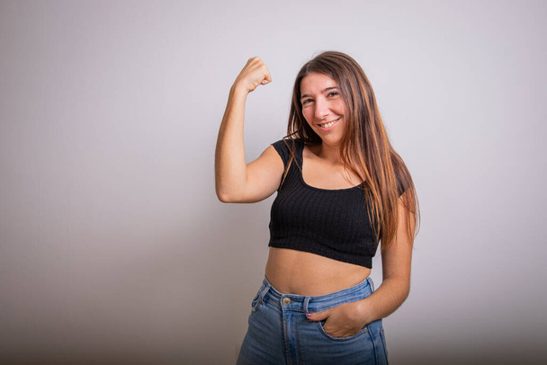 Chica levanta el brazo y muestra su bíceps, concepto de empoderamiento femenino. Estudio fotografía - Foto, imagen
