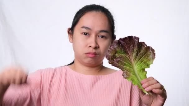 Mujer asiática odia la ensalada fresca sobre fondo blanco en el estudio. Concepto de dieta y alimentos saludables. - Metraje, vídeo