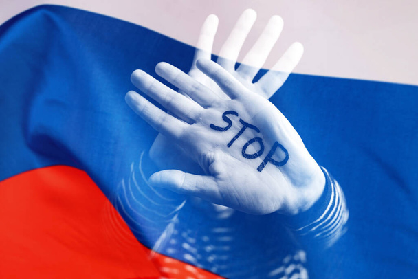 War between Russia and Ukraine. Woman with sad sight, Stop text over Russian flag. - Фото, изображение