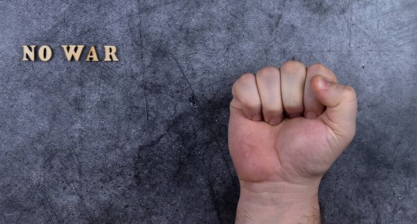 сжатый кулак и надпись: "Нет войны". темный, мрачный бетонный фон. концепция отрицания военных действий. остановить агрессию - Фото, изображение