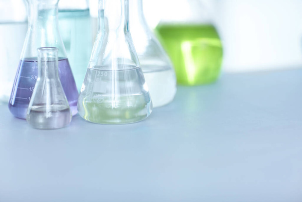 Compuestos químicos. Viales llenos de líquido colorido sobre una mesa en un laboratorio. - Foto, Imagen