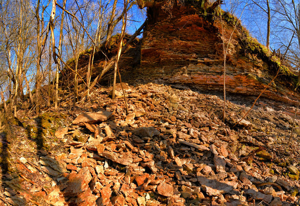 Fragmenty skał stopniowo schodzą w dół stoku w kanionie rzeki Ławy w regionie Leningradu.  - Zdjęcie, obraz