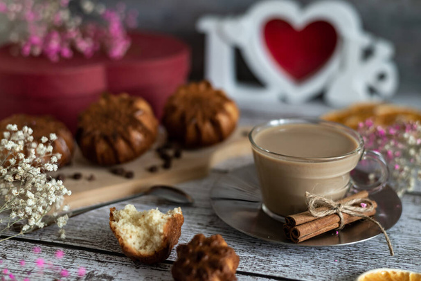 Composition d'un délicieux petit déjeuner festif muffins faits maison et une tasse de café latte sur un fond clair en bois, des fleurs et une boîte rouge, gros plan. - Photo, image