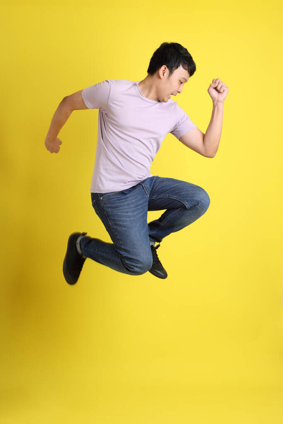 The young adult Asian man standing on the yellow background. - Foto, Imagen