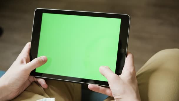 Un jeune homme joue un simulateur de course sur une tablette. Ecran vert pour un remplacement rapide sur votre vidéo. Gros plan d'un mans mains avec une tablette, vue d'en haut. - Séquence, vidéo