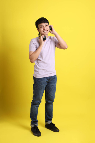 Mladý dospělý asijský muž stojící na žlutém pozadí. - Fotografie, Obrázek