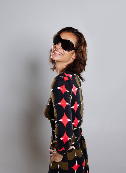 Stylish confidence. Studio shot of a woman wearing sunglasses and a geometric print dress. - Valokuva, kuva