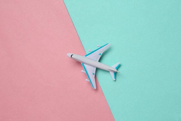 Avión de pasajeros de juguete sobre un fondo azul rosado. Viaje, concepto de viaje. Vista superior - Foto, imagen
