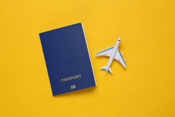Toy passenger plane and passport on yellow background. Voyage, Travel, summer vacation concept. Top view - Photo, Image