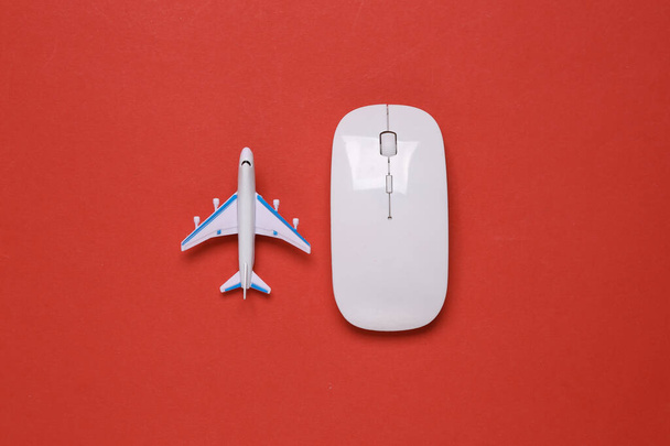 赤い背景におもちゃの旅客機とPCマウス - 写真・画像