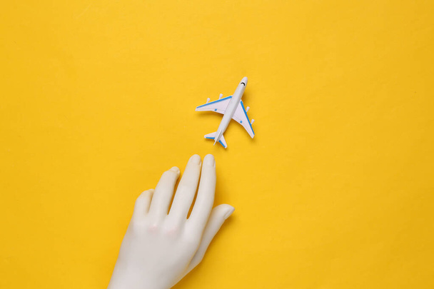 Toy passenger plane and hand on yellow background. Travel concept - 写真・画像