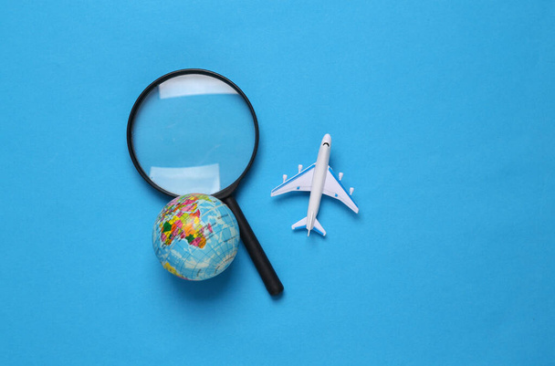 Juguete avión de pasajeros, globo y lupa sobre fondo azul. Viaje, viaje, concepto de vacaciones de verano. Vista superior - Foto, imagen