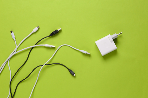 Different usb cables and charger on green background. Eco concept. Top view - Фото, изображение