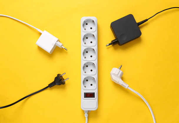 Electrical Extension cord with different plugs and adapters on yellow background. Top view. - Photo, Image
