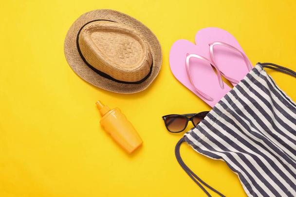 Beach bag with beach accessories on a yellow background. Top view. Flat lay - Фото, зображення