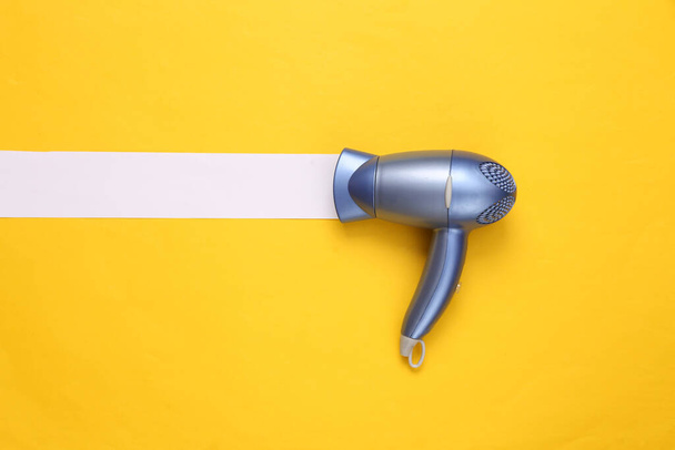 Hair dryer with white line on yellow background. Minimal beauty layout. Top view. Flat lay - Photo, Image