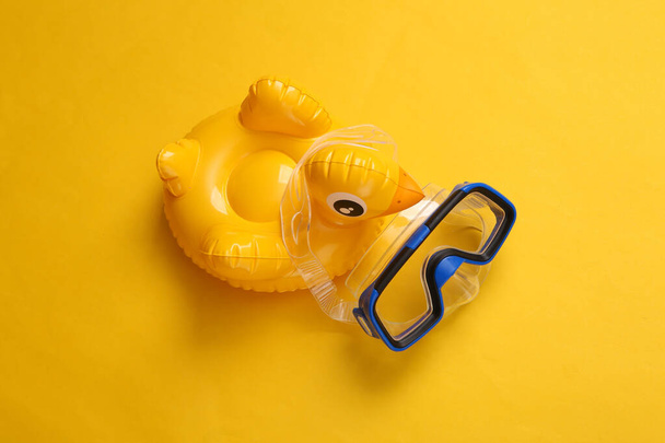 Aufblasbare Ente mit Tauchermaske auf gelbem Hintergrund. Minimaler Sommer, Strandruhekonzept. Ansicht von oben. - Foto, Bild