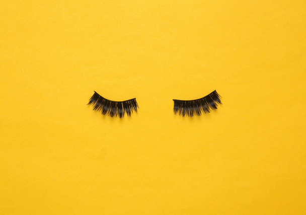 False eyelashes on a yellow background. Beauty concept - Photo, Image