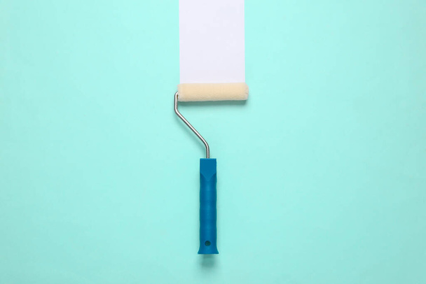 Краска ролика с белой полосой на синем фоне. Концепция ремонта дома  - Фото, изображение