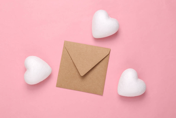 Liefdesbrief. Envelop met witte hartjes op een roze pastelachtergrond - Foto, afbeelding