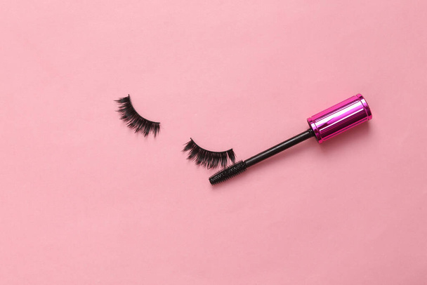 False eyelashes and eyelash brush with mascara on pink background. Creative flat lay, beauty concept - Φωτογραφία, εικόνα