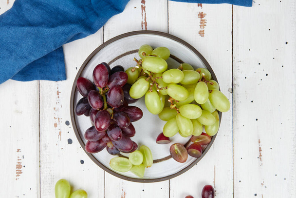 Bunches of fresh ripe green and red grapes on a wooden table - Photo, Image