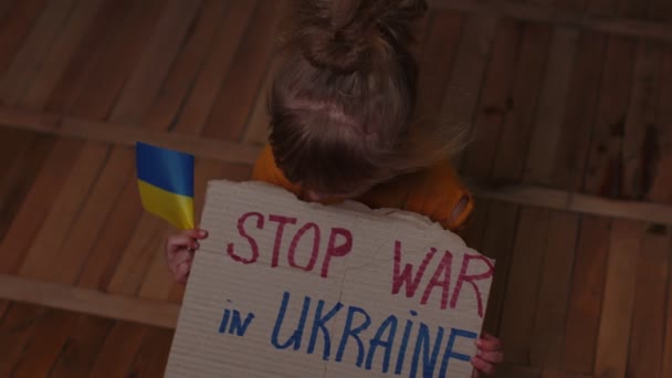 Φοβισμένο κορίτσι από την Ουκρανία, επιγραφή μασάζ Σταματήστε τον πόλεμο στην Ουκρανία κρύβονται από βομβιστική επίθεση στο σπίτι - Πλάνα, βίντεο