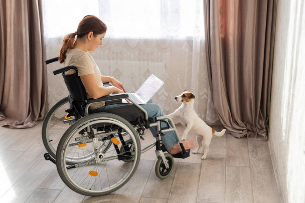 Una mujer en silla de ruedas usa un portátil. - Foto, Imagen