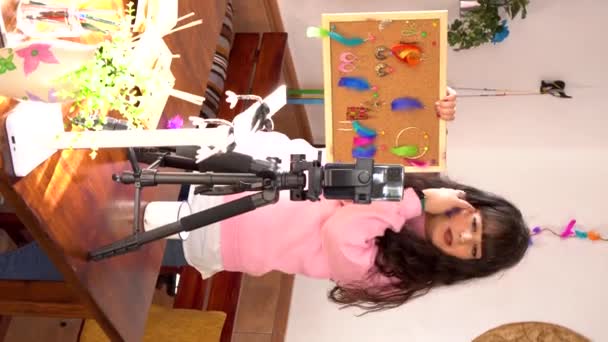 Vídeo em formato vertical: Criativa designer feminina mostrando placa com brincos coloridos feitos à mão e gravação de vídeo para blog no smartphone em estúdio de arte - Filmagem, Vídeo