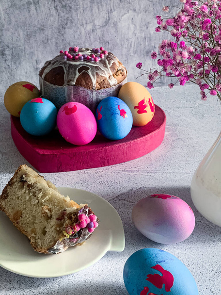 Tradiční velikonoční jídlo pravoslavného velikonočního dortu a barevných malovaných vajec, kus muffinu na desce vertikální foto světlo pozadí detail - Fotografie, Obrázek