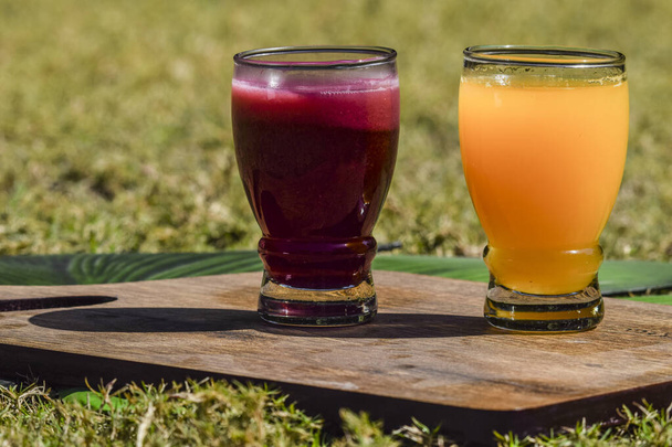 Suco de romã e suco de laranja suco de malta em vidro transparente no fundo da grama. Sumo de anaar santra ras em tábua de madeira - Foto, Imagem