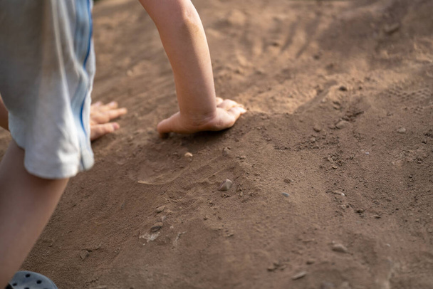 Το παιδί σκαρφαλώνει σε ένα σωρό άμμου - Φωτογραφία, εικόνα