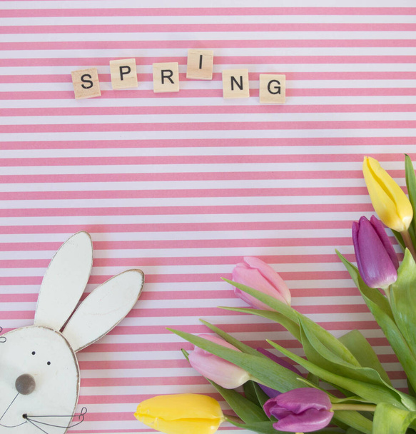 vaaleanpunainen, keltainen ja violetti tulppaanit vaaleanpunainen ja valkoinen raidallinen maahan puinen pääsiäinen kani keväällä tausta - Valokuva, kuva