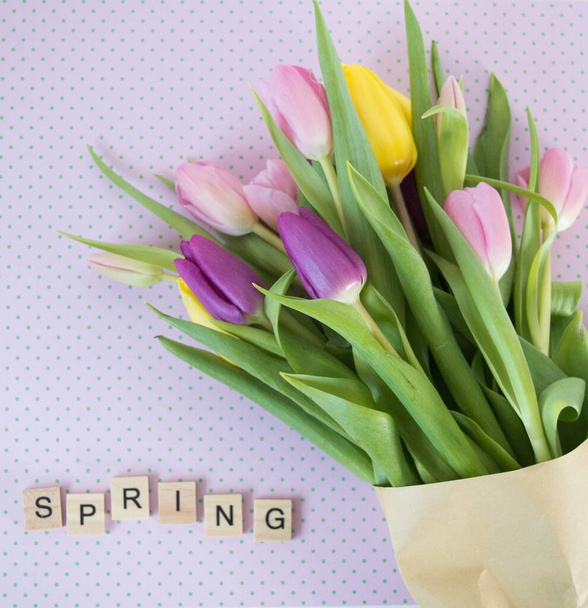 yellow, pink and purple tulips on patterned ground with wooden letters sping background - Fotografie, Obrázek