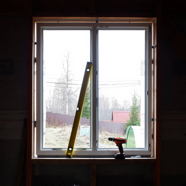 Einbau von Fenstern in einem Fachwerkhaus. den Füllstand und den Schraubendreher im Hintergrund des eingebauten Fensters. Kopierraum. - Foto, Bild