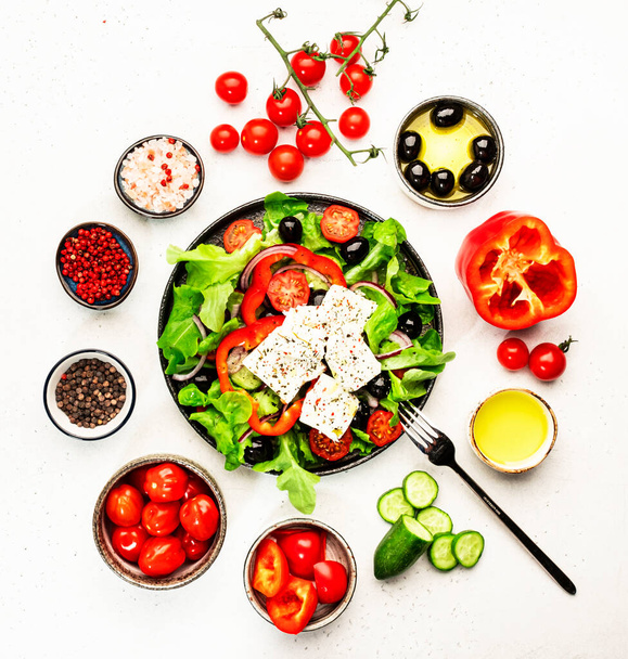 Greek salad with feta cheese, olives, cherry tomato, paprika, cucumber and red onion, healthy vegeterian mediterranean diet food, low calories eating. White stone background, top view - Фото, изображение