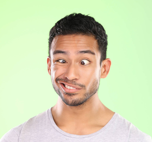 Ah duh. Cropped shot of a handsome young man making a face against a green background in studio. - Foto, Imagem